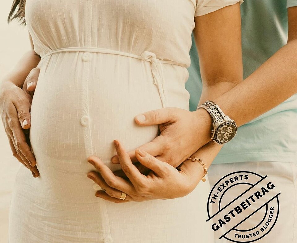 Schwangerne Frau wird vom Vater umarmt in der Hotellobby